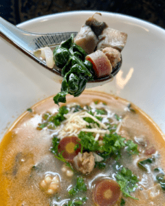 vegan sausage and couscous soup with kale, carrot, fennel