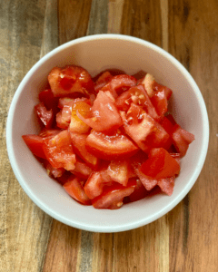 tomatoes for Vegan Antipasto couscous salad loaded with vegan sausage, vegan cheese, kale, spinach, cucumbers, tomatoes, onions, fennel, herbs, olives and toasted almonds.