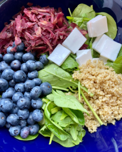 vegan Rosemary Almond Salad, made with spinach, arugula, blueberries, pear, vegan feta, quinoa, carrots, toasted almonds and a rosemary dressing.