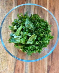 parsley and basil for Vegan Antipasto couscous salad loaded with vegan sausage, vegan cheese, kale, spinach, cucumbers, tomatoes, onions, fennel, herbs, olives and toasted almonds.