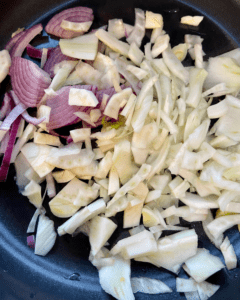 red onion and fennel for Vegan Antipasto couscous salad loaded with vegan sausage, vegan cheese, kale, spinach, cucumbers, tomatoes, onions, fennel, herbs, olives and toasted almonds.