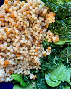 Vegan Antipasto couscous salad loaded with vegan sausage, vegan cheese, kale, spinach, cucumbers, tomatoes, onions, fennel, herbs, olives and toasted almonds.