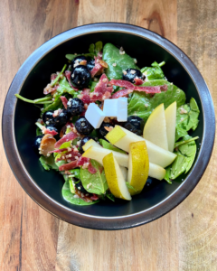 vegan Rosemary Almond Salad, made with spinach, arugula, blueberries, pear, vegan feta, quinoa, carrots, toasted almonds and a rosemary dressing.