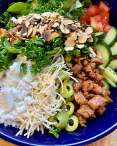 Vegan Antipasto couscous salad loaded with vegan sausage, vegan cheese, kale, spinach, cucumbers, tomatoes, onions, fennel, herbs, olives and toasted almonds.