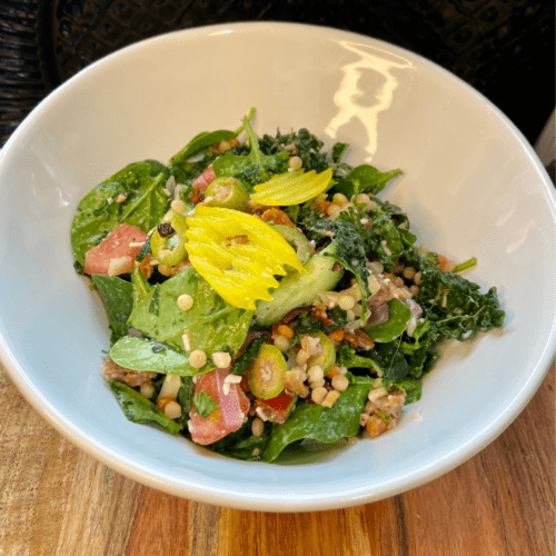 vegan antipasto couscous salad. Made with Italian seasoning, vegan sausage, vegan cheese, olives, kale, spinach, cucumber, tomato, almonds