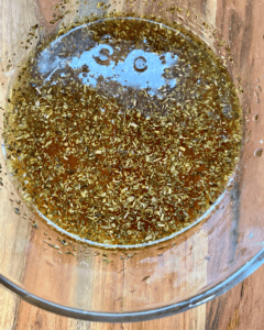 Italian dressing for Vegan Antipasto couscous salad loaded with vegan sausage, vegan cheese, kale, spinach, cucumbers, tomatoes, onions, fennel, herbs, olives and toasted almonds.