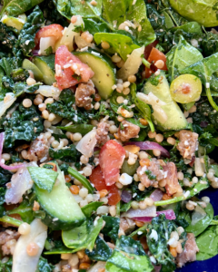 Vegan Antipasto couscous salad loaded with vegan sausage, vegan cheese, kale, spinach, cucumbers, tomatoes, onions, fennel, herbs, olives and toasted almonds.