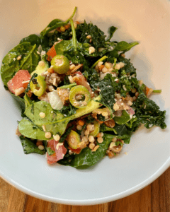 Vegan Antipasto couscous salad loaded with vegan sausage, vegan cheese, kale, spinach, cucumbers, tomatoes, onions, fennel, herbs, olives and toasted almonds.