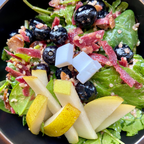 vegan Rosemary Almond Salad, made with spinach, arugula, blueberries, pear, vegan feta, quinoa, carrots, toasted almonds and a rosemary dressing.