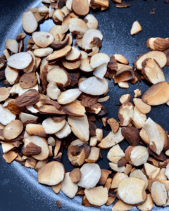 toasted almonds for Vegan Antipasto couscous salad loaded with vegan sausage, vegan cheese, kale, spinach, cucumbers, tomatoes, onions, fennel, herbs, olives and toasted almonds.