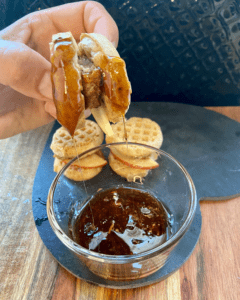 Vegan Waffle Sliders with Rosemary Maple. Vegan breakfast sausage and sliced apple, sandwiched between mini waffles and dipped in rosemary maple syrup.