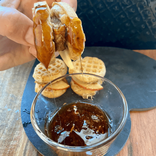 Vegan Waffle Sliders with Rosemary Maple. Vegan breakfast sausage and sliced apple, sandwiched between mini waffles and dipped in rosemary maple syrup.