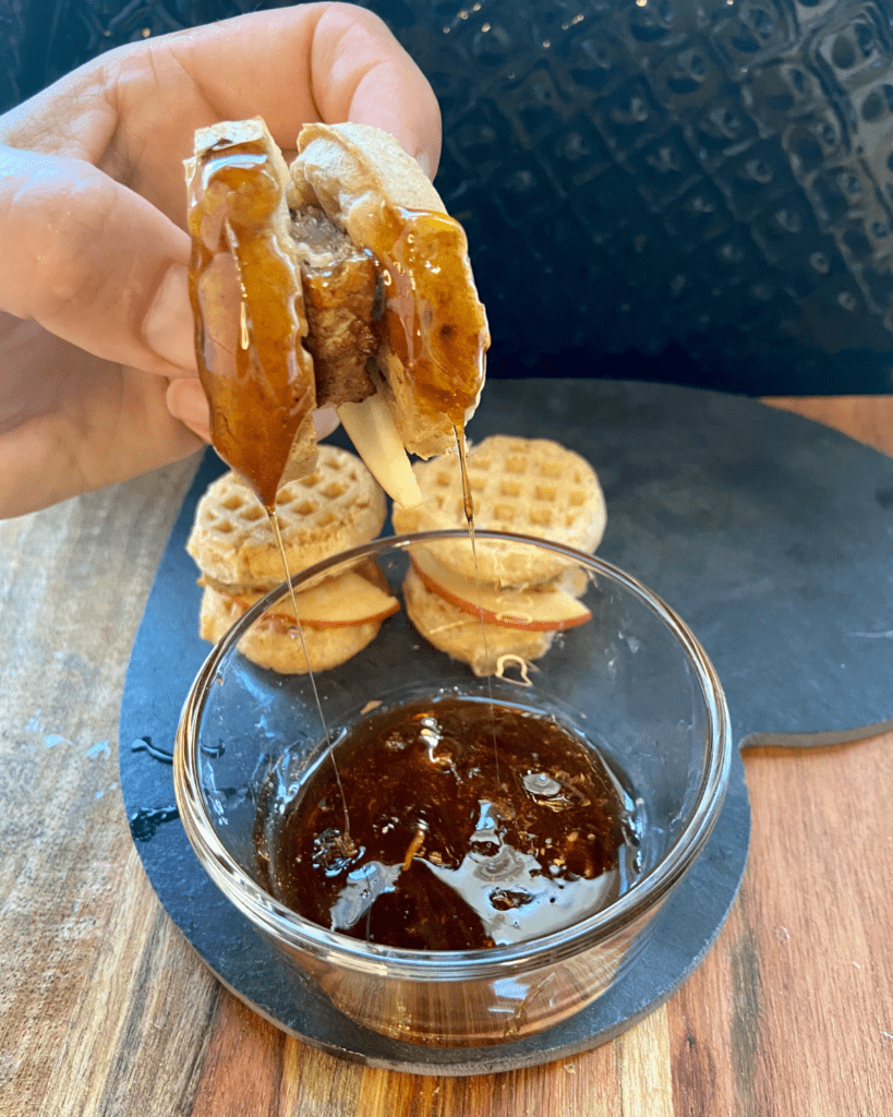 Vegan Waffle Sliders with Rosemary Maple.  Vegan breakfast sausage and sliced apple, sandwiched between mini waffles and dipped in rosemary maple syrup. 