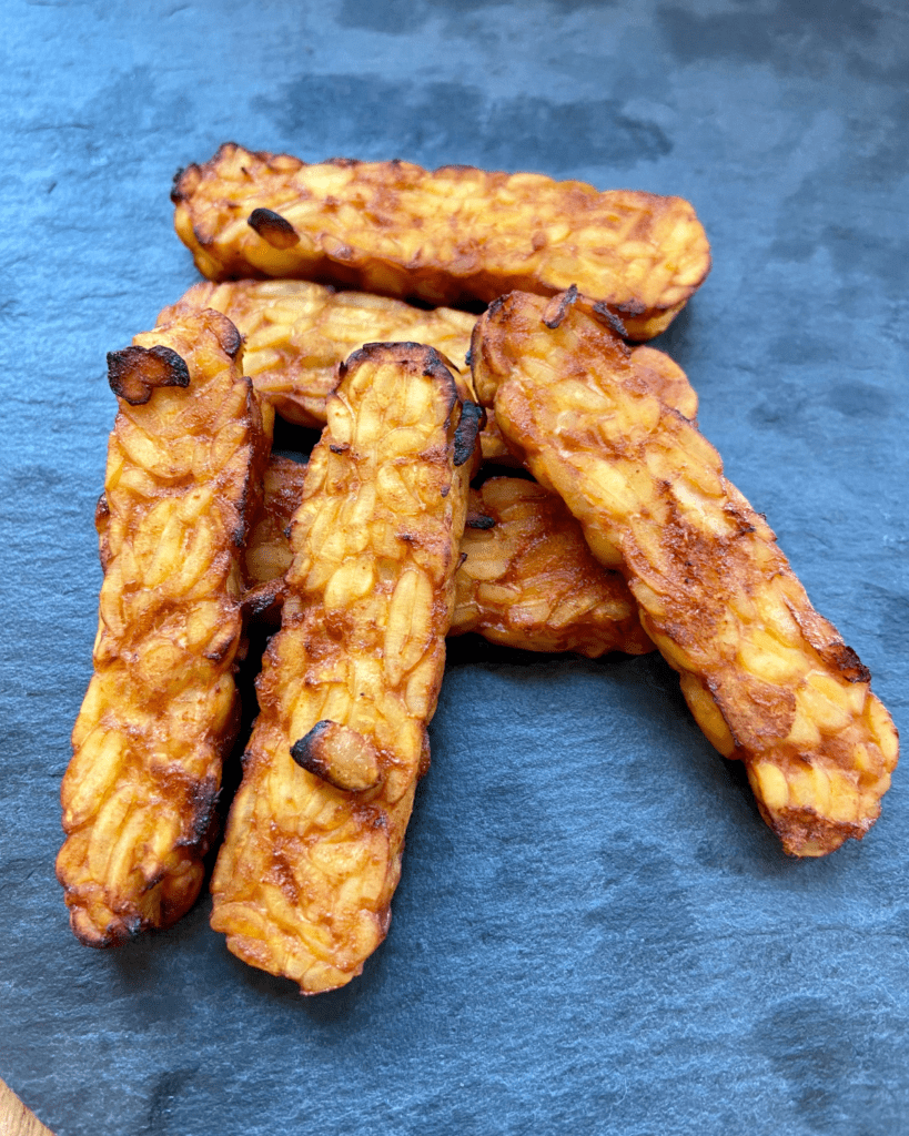 tempeh for Toasted macadamia nut and kale salad, served with seasoned quinoa, topped with sauerkraut and smoky tempeh. 