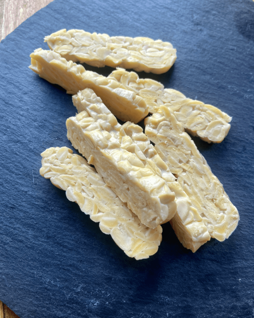 tempeh for Toasted macadamia nut and kale salad, served with seasoned quinoa, topped with sauerkraut and smoky tempeh. 