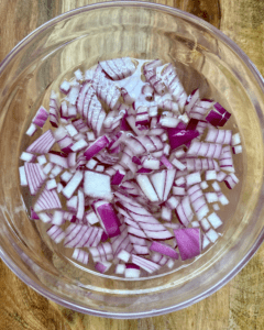 red onion for Vegan taco stuffed with spicy five spice tofu crumble, Asian red pepper slaw, fresh sliced avocado, green onion.