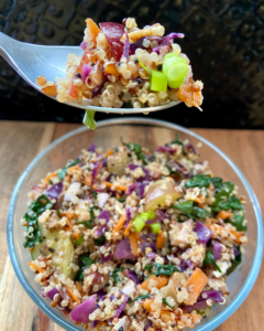 Tofu and almond quinoa salad made with grapes, kale, cabbage, carrots, cucumbers, and a savory Asian dressing. 