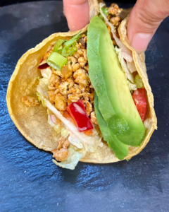 Vegan taco stuffed with spicy five spice tofu crumble, Asian red pepper slaw, fresh sliced avocado, green onion.