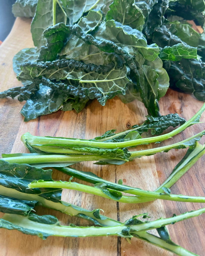 de-stemming kale for Tofu Almond Quinoa Salad made with grapes, kale, cabbage, carrots, cucumbers, and a savory Asian dressing. 