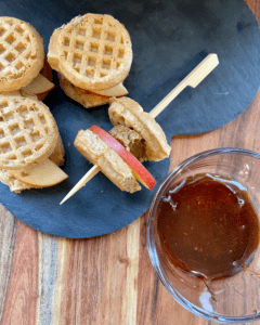 Vegan Waffle Sliders with Rosemary Maple. Vegan breakfast sausage and sliced apple, sandwiched between mini waffles and dipped in rosemary maple syrup.