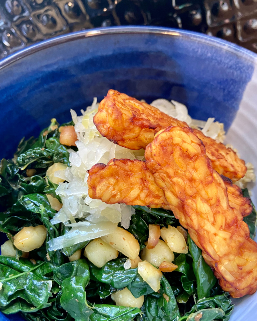 Toasted macadamia nut and kale salad, served with seasoned quinoa, topped with sauerkraut and smoky tempeh. 