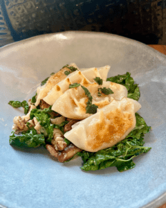 vegan butternut squash dumplings served with shiitake mushrooms and kale in a miso butter