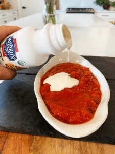 miyokos liquid mozzarella being poured over sauce