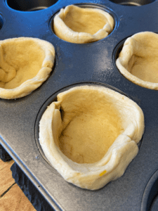 putting dough in muffin tin for Just Egg Quiche cups