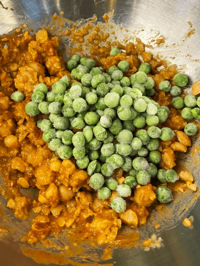 adding peas to curry chickpeas