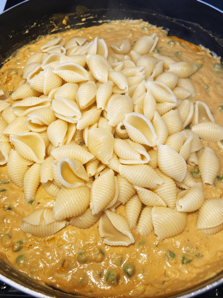 adding pasta to  vegan Mac and cheese sauce in pan