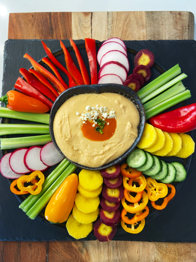 white bean buffalo dip with vegan blue cheese crumbles served with vegetables 