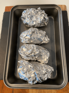 potatoes wrapped in tin foil for vegan Irish loaded baked potatoes