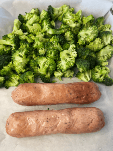 vegan bangers and broccoli on baking tray