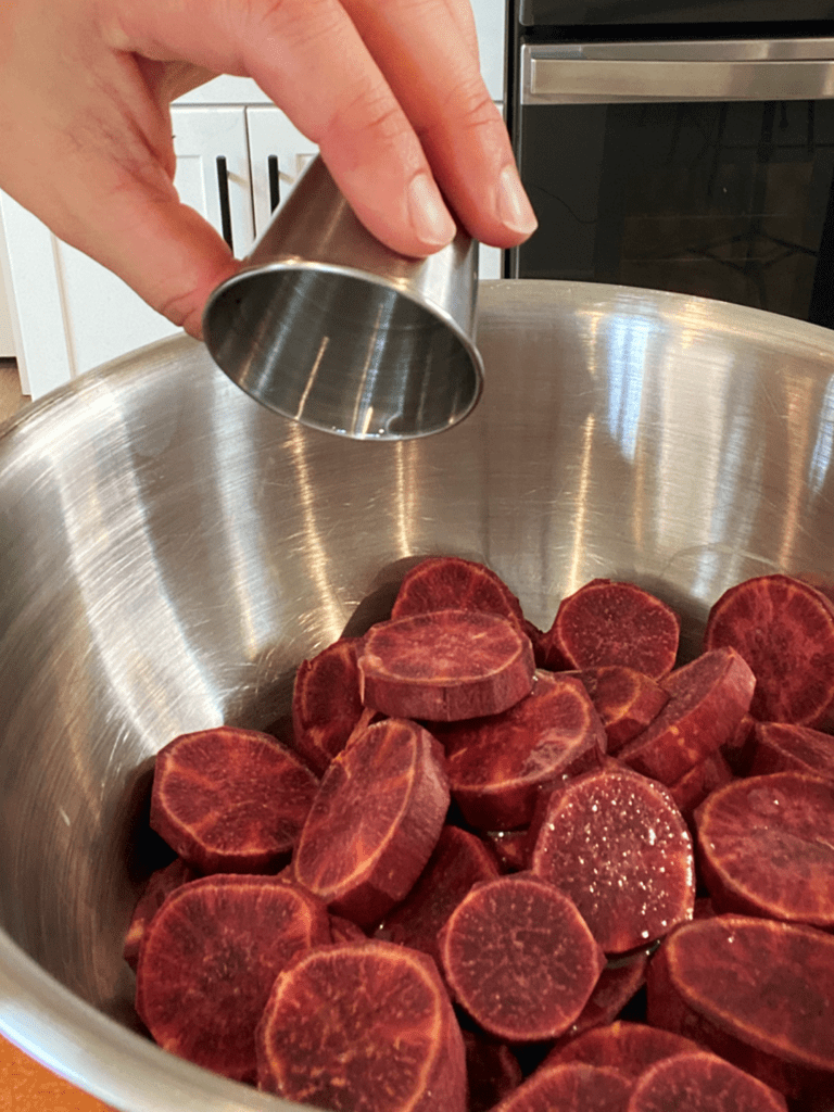 Adding oil to sliced purple sweet potatoes