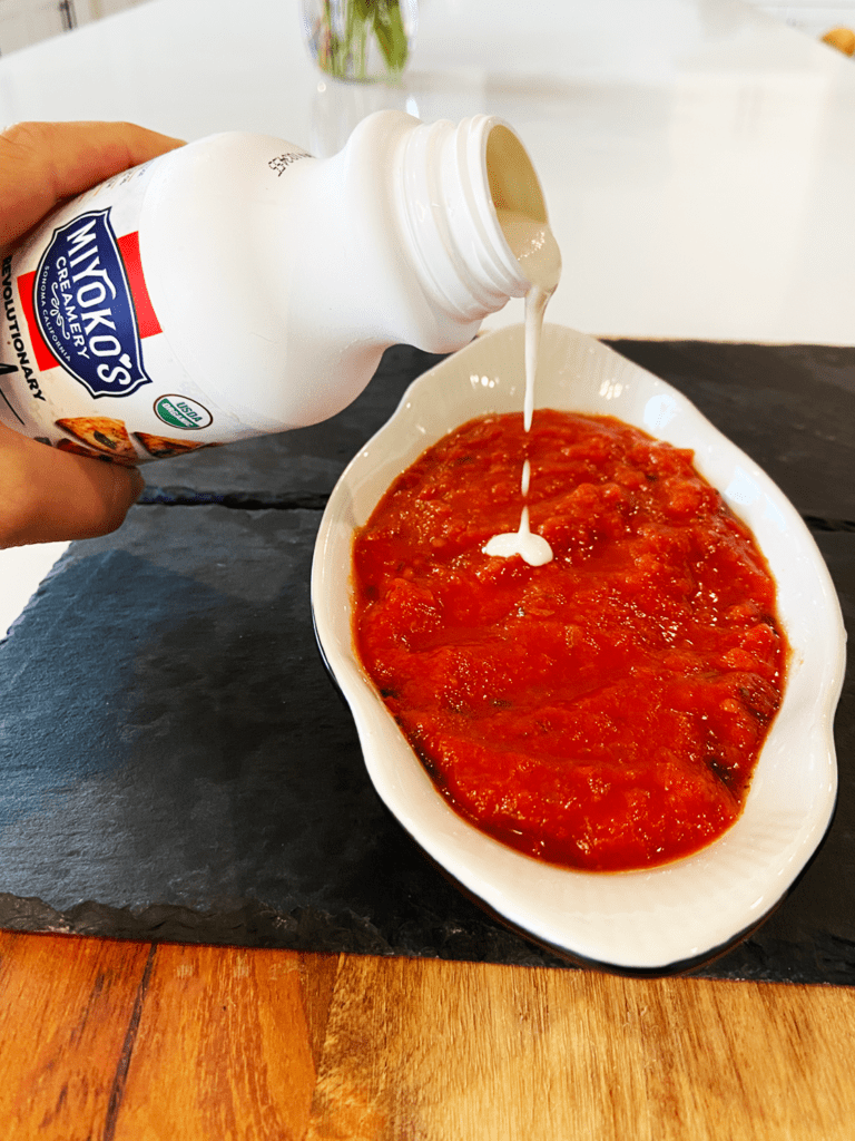 vegan mozzarella cheese being poured on sauce