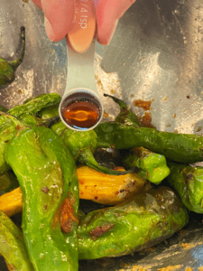 adding toasted sesame oil to miso shishito peppers